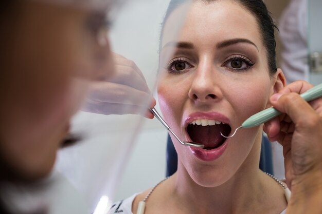 Dentista examinar uma paciente do sexo feminino com ferramentas