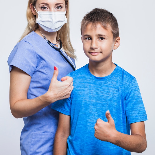 Dentista feminina e menino gesticulando polegares para cima