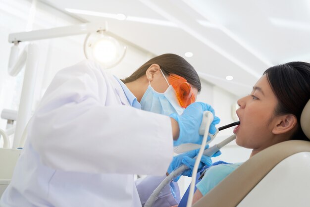 Dentista feminina, tratando os dentes do paciente na clínica