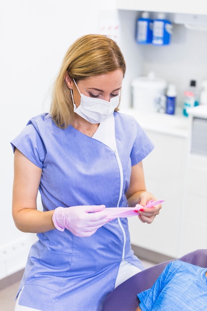 Dentista feminina usando luvas cor de rosa na clínica