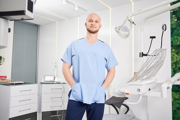 Dentista masculino bonito em pé no consultório odontológico