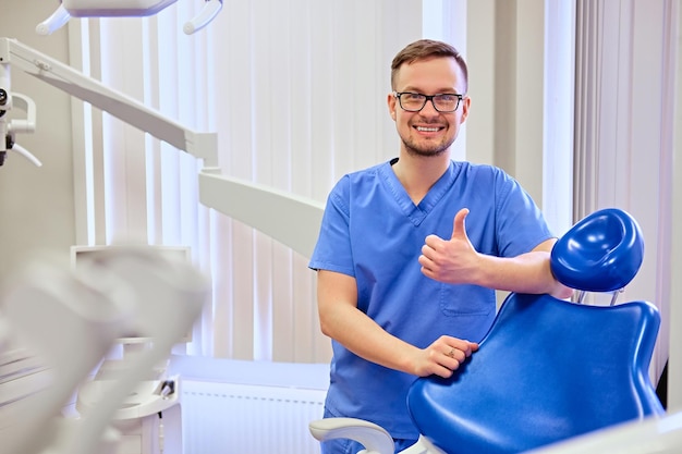 Dentista masculino bonito em uma sala com equipamento médico em segundo plano.