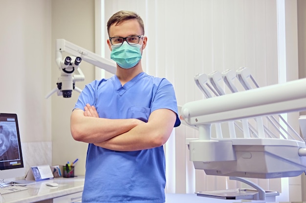 Dentista masculino em uma sala com equipamento médico em segundo plano.