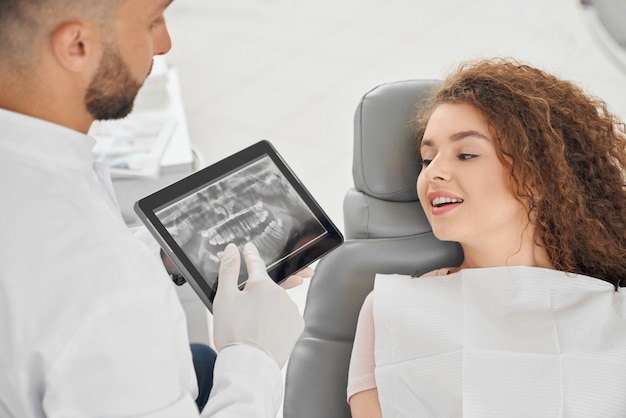 Foto grátis dentista masculino qualificado mostrando imagem de raio x dos dentes para mulher