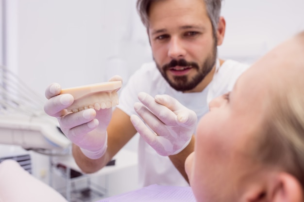 Dentista mostrando modelo de prótese para o paciente