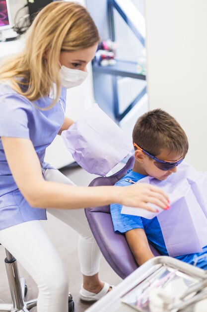 Dentista, preparando o menino para check-up odontológico