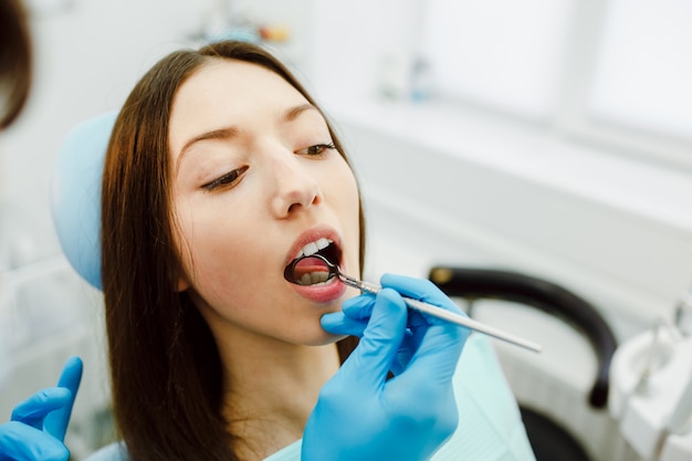 Dentista que examina os dentes de jovem