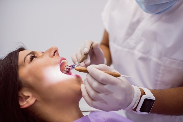 Dentista que examina os dentes pacientes do sexo feminino