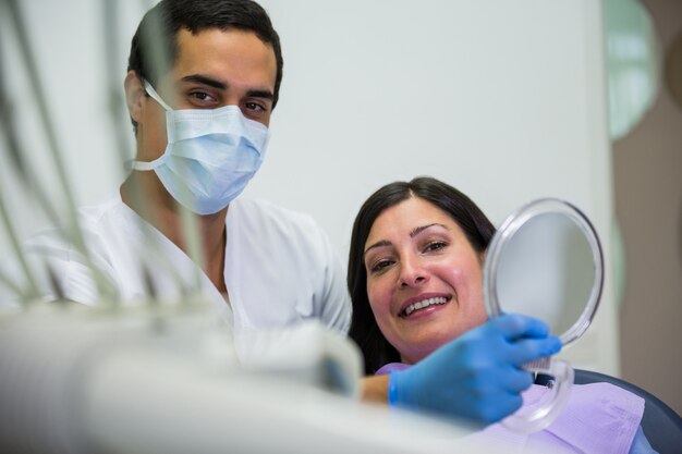 Dentista segurando o espelho na frente do paciente