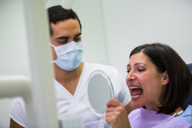 Dentista segurando o espelho na frente do paciente
