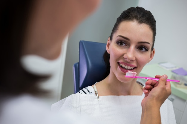 Dentista segurando uma escova na frente do paciente