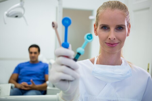 Dentista sorridente segurando ferramentas dentárias