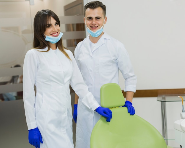 Foto grátis dentistas com máscaras cirúrgicas e luvas posando enquanto sorrindo