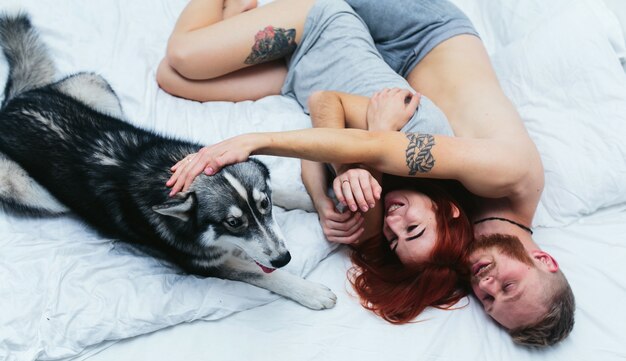 Descontraído casal na cama com seu animal de estimação