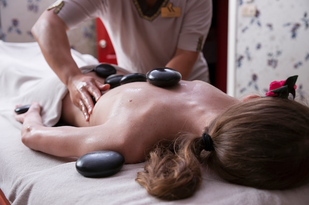 Foto grátis descontraído mulher recebendo uma massagem com pedras quentes