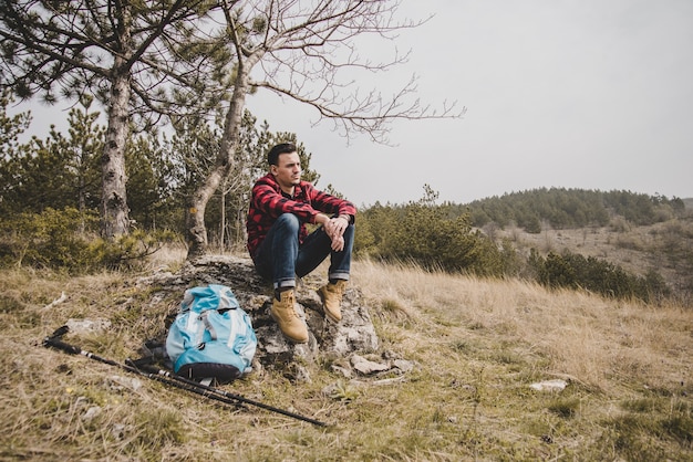 Descontraído viajante descansando sobre uma pedra