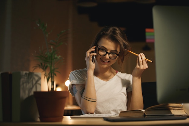 Desenhista concentrado da mulher que fala pelo telefone móvel