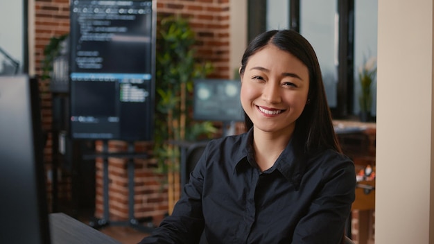 Desenvolvedor de software sorridente digitando o código do aplicativo de aprendizado de máquina no teclado do computador sentado na mesa no escritório de big data. programador de nuvem amigável trabalhando casualmente na agência de segurança cibernética.