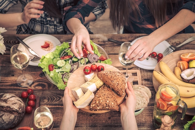 Desfrutando de um jantar com meus amigos. Vista superior de um grupo de pessoas jantando juntas, sentadas em uma mesa de madeira rústica, o conceito de celebração e comida caseira saudável