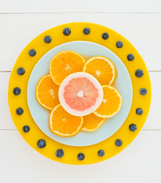 Foto grátis design decorativo feito com fatias de laranja e grapefruit e mirtilos na mesa de madeira