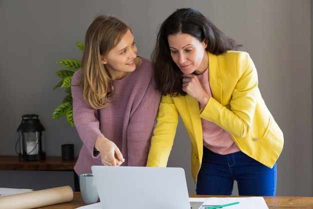 Designer de interiores feminino e cliente usando o computador portátil