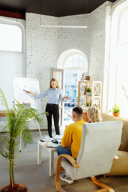 Designer de interiores trabalhando com jovem casal. família adorável e designer ou arquiteto profissional discutindo o conceito do futuro interior, trabalhando com paleta de cores, desenhos de quartos em um escritório moderno.