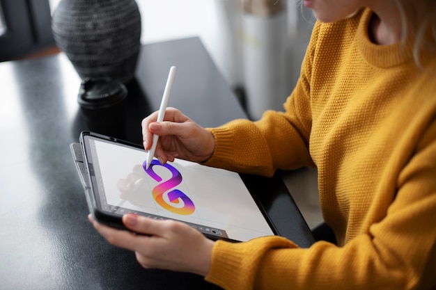 Designer de logotipo feminino trabalhando em um tablet gráfico