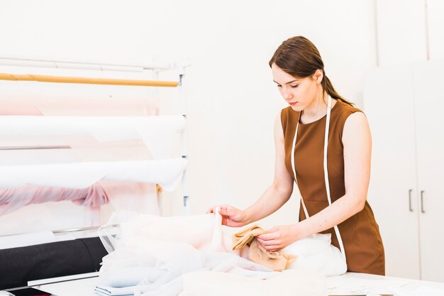 Designer de moda feminina bonita escolhendo tecido no estúdio