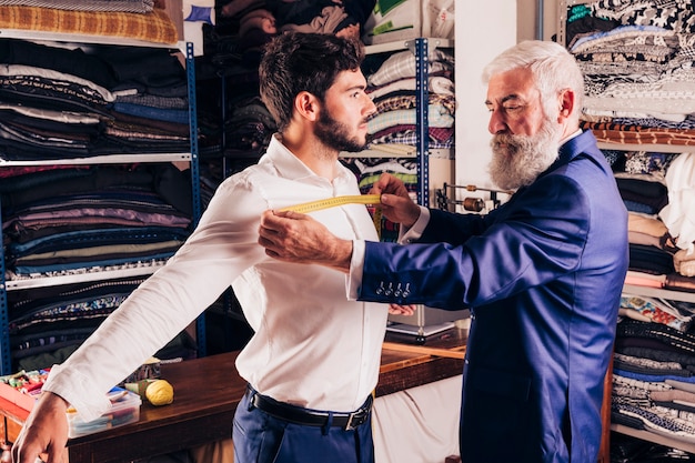 Designer de moda masculina profissional, tendo a medição do peito do seu cliente