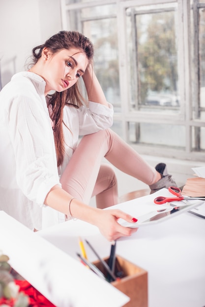 Designer de moda mulher trabalhando em estúdio, sentado na mesa