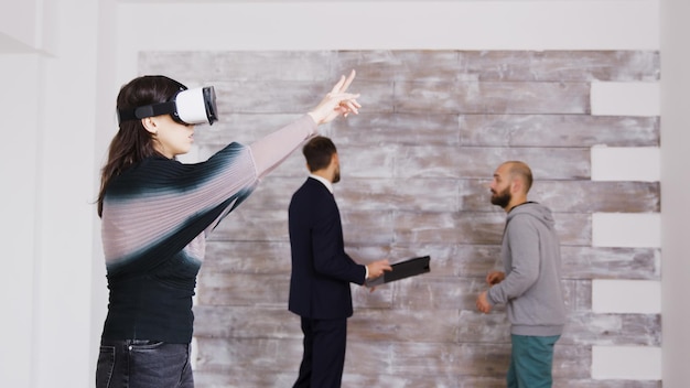 Foto grátis designer feminina com óculos de realidade virtual em um apartamento vazio, enquanto o agente imobiliário está falando com o dono da casa ao fundo.