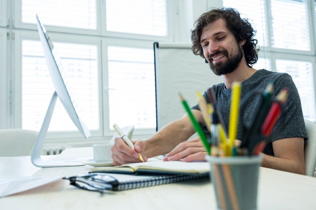 Foto grátis designer gráfico homem escrevendo em um diário