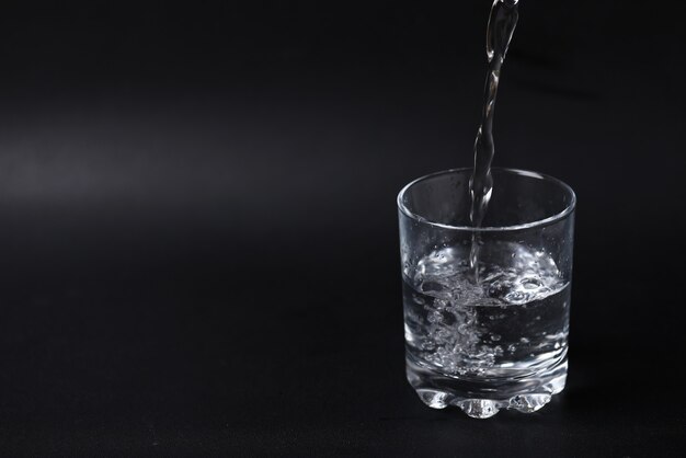 Despejando água em um copo meio cheio.