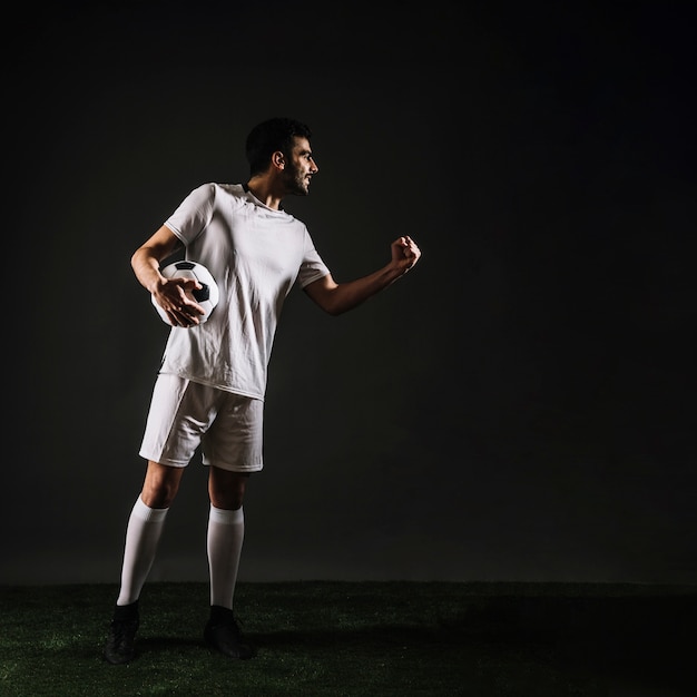 Desportista atraente com bola comemorando a vitória