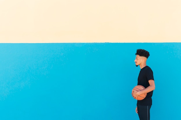 Desportista étnica com cabelo encaracolado em pé com basquete