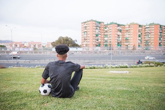 Desportista sentado na grama em ambiente urbano
