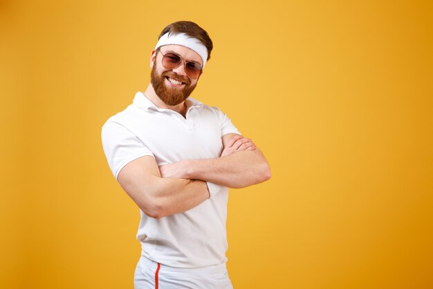 Desportista sorridente em óculos de sol com braços cruzados