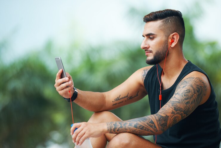 Foto grátis desportista tatuada com telefone ao ar livre