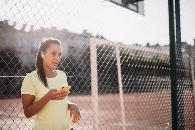 Desportista usando smartphone e fones de ouvido no estádio