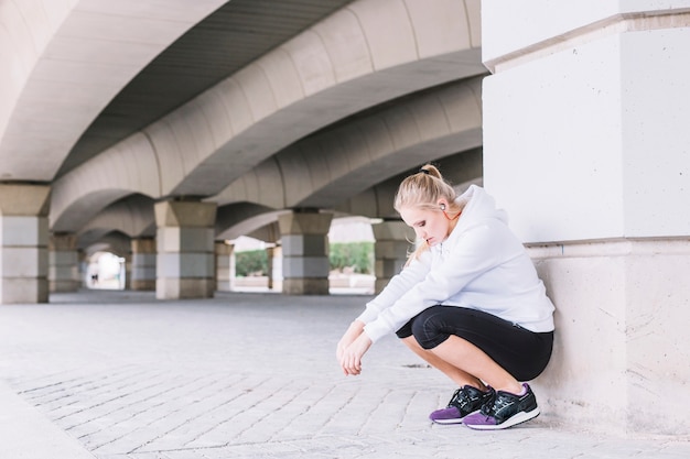 Foto grátis desportiva mulher sentada perto da coluna