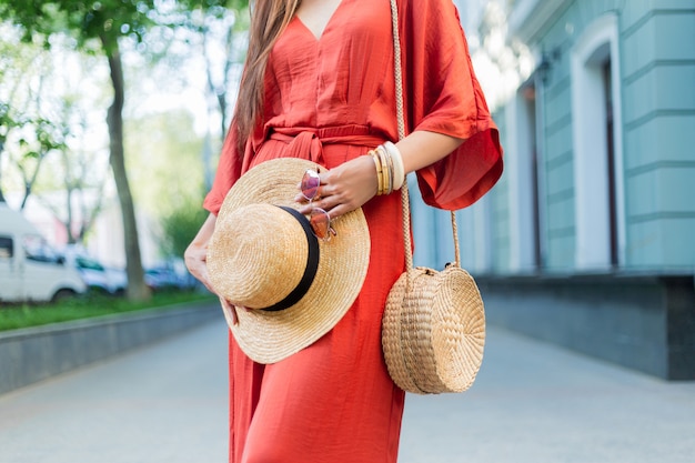 Detalhes de moda. Mulher de vestido de verão coral elegante incrível posando na rua
