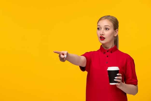 Dia da camisa vermelha linda garota apontando para a frente em uma camisa vermelha em um fundo amarelo