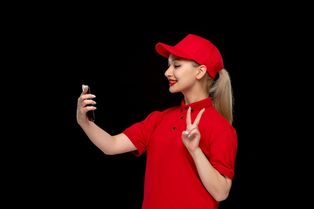 Dia da camisa vermelha linda garota sorrindo e falando selfie no boné vermelho vestindo camisa e batom brilhante
