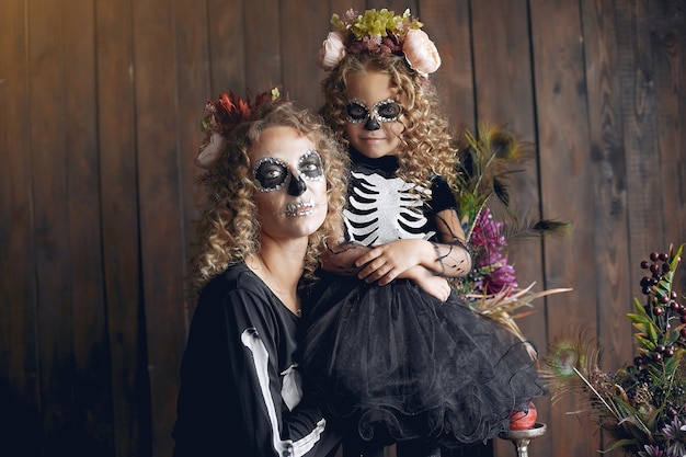 Dia das Bruxas. Mãe e filha em traje de halloween de estilo mexicano. Família em casa.