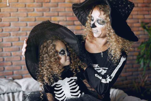 Dia das Bruxas. Mãe e filha em traje de halloween de estilo mexicano. Família em casa.