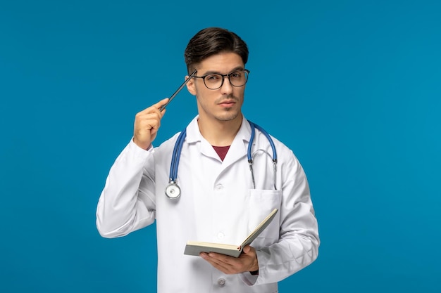 Dia dos médicos bonitão moreno bonito em vestido médico apontando caneta para templos com o livro