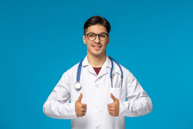 Dia dos médicos bonitão moreno bonito em vestido médico mostrando um bom gesto e sorrindo