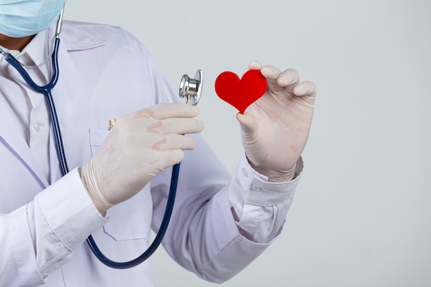 Dia mundial da diabetes; médico segurando um estetoscópio e um coração vermelho em forma de madeira