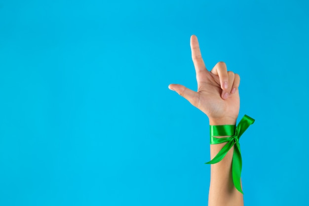 Dia mundial da saúde mental. fitas verdes amarradas no pulso em fundo azul