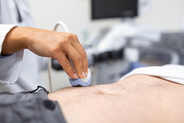 Diagnóstico por ultrassom do estômago na cavidade abdominal de um homem na clínica vista de perto o médico executa um sensor de ultrassom sobre o abdômen masculino do paciente diagnóstico de órgãos internos